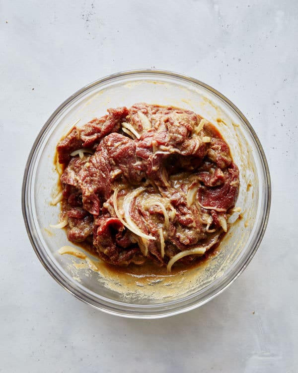 Beef mixed together in a bowl with marinade to make Korean bulgogi.