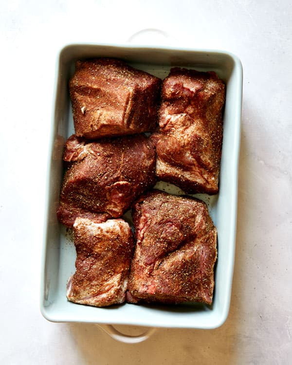 Pork shoulder rubbed with spices in a baking dish.  