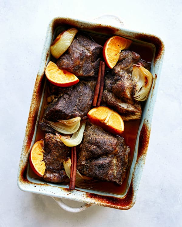 Carnitas in a baking dish to be shredded. 