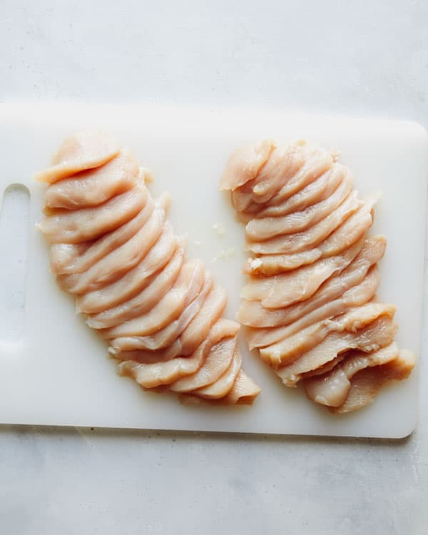 Chicken breast cut up on a cutting board.