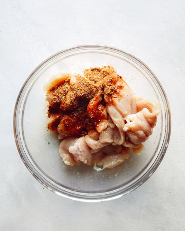 Chicken cut up in a bowl with fajita seasonings.