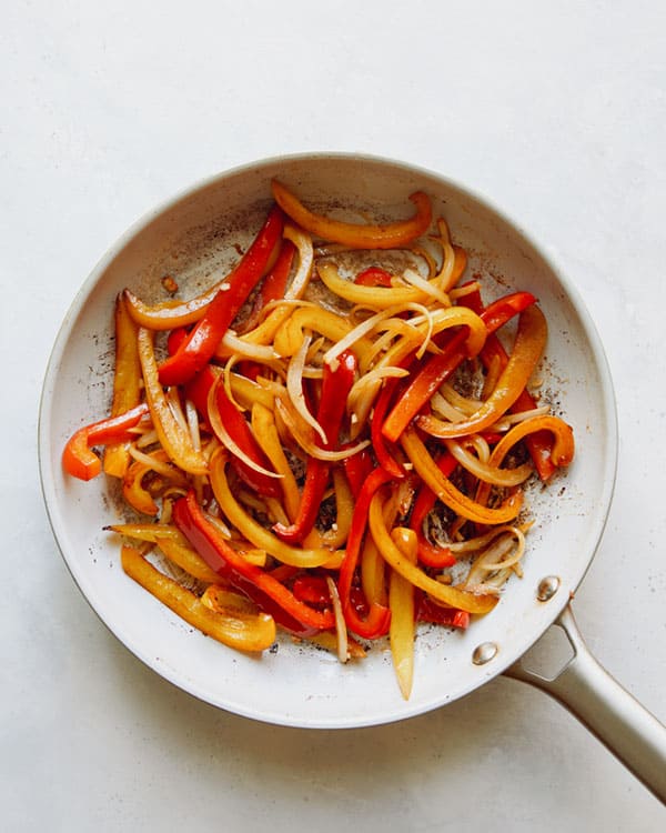 Bell peppers cooking in a skillet.