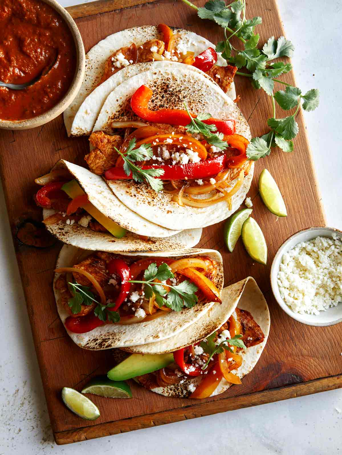 Chicken fajitas in tortillas on a board.