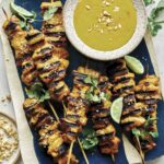 Chicken satay recipe on a platter with sauce.