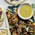 Chicken satay recipe on a platter with sauce.