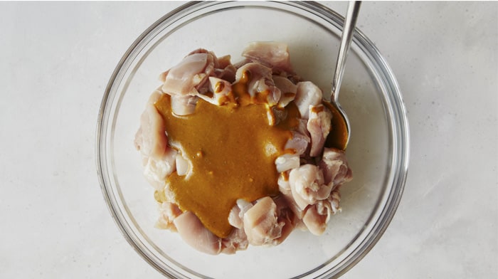 Chicken satay marinade in a bowl with chicken.