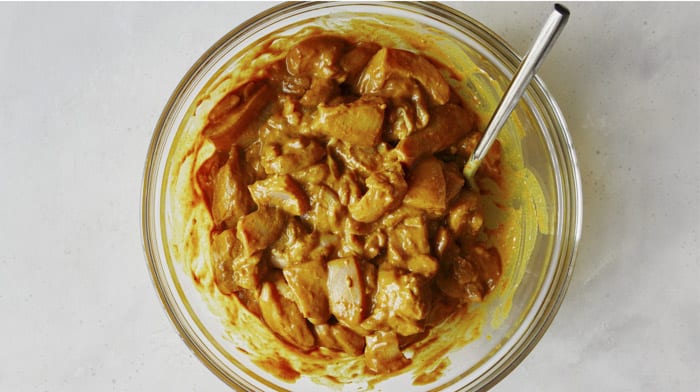 Chicken marinating in a glass bowl.