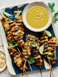 Chicken satay recipe with a peanut sauce on a platter.