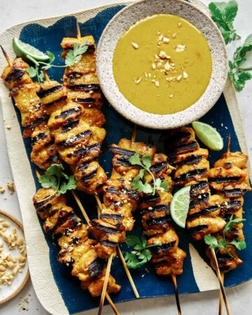 Chicken satay recipe with a peanut sauce on a platter.