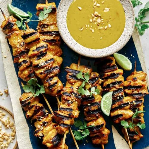Chicken satay recipe with a peanut sauce on a platter.
