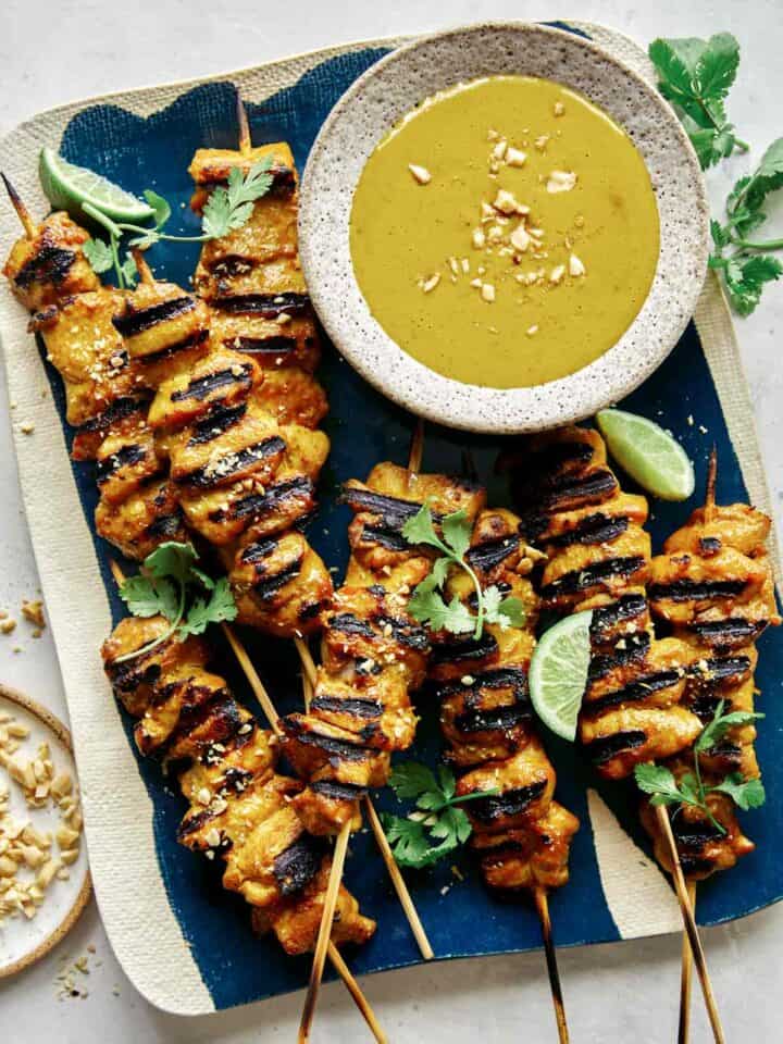 Chicken satay recipe with a peanut sauce on a platter.