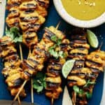 Chicken satay recipe on a platter with sauce.