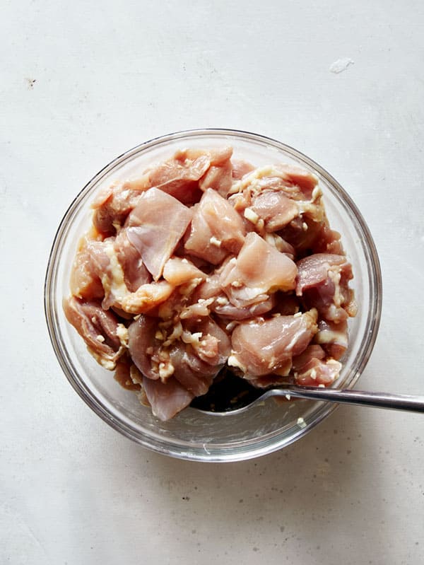 Chicken marinating in a glass bowl to make honey garlic chicken.