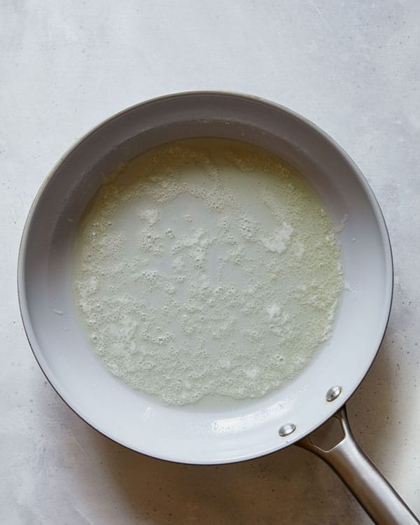 Melted butter in a skillet to make honey garlic chicken. 