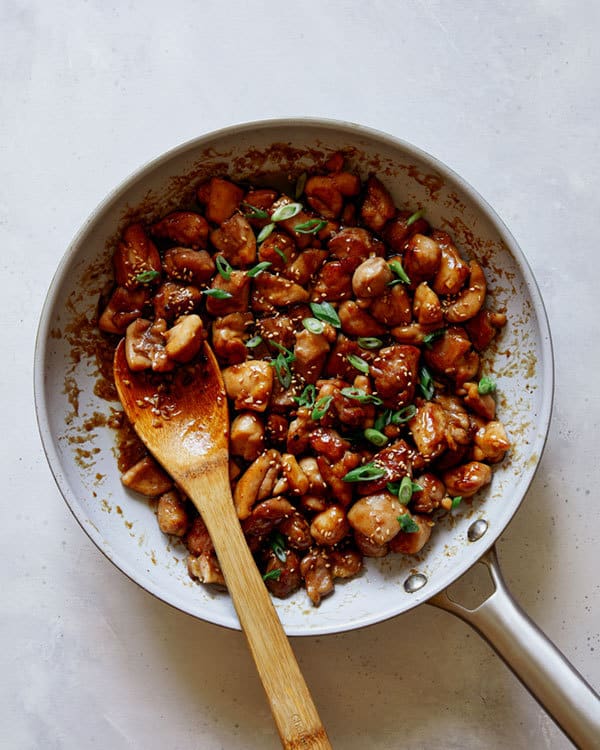 Honey garlic chicken in a skillet with a spoon.