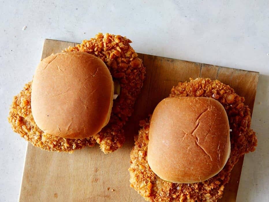 Overhead image of two pork tenderloin sandwiches on a cutting board.