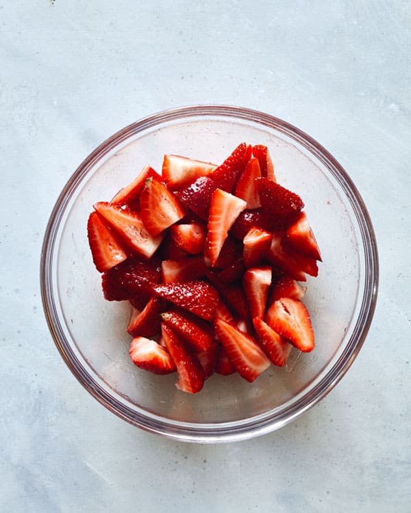 Strawberry ingredients for strawberry shortcake in a bowl mixed together.