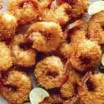 Coconut shrimp with lime wedges on a platter.