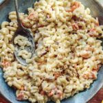 Hawaiian style macaroni salad in a bowl with serving bowls nearby.