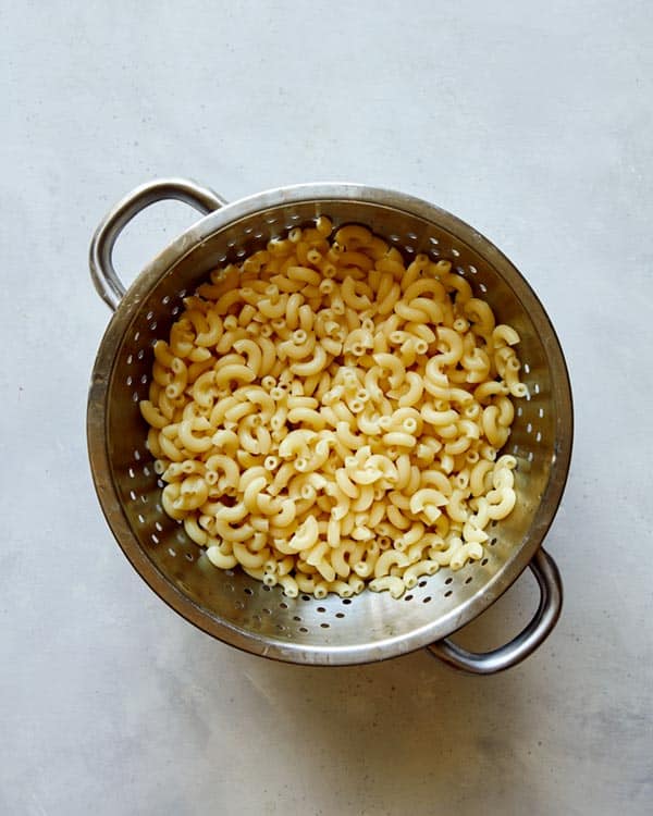 Cooked elbow macaroni in a colander. 
