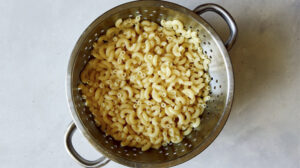 Cooked elbow macaroni in a colander.
