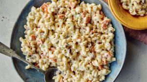 Hawaiian style macaroni salad in a bowl with serving bowls nearby.