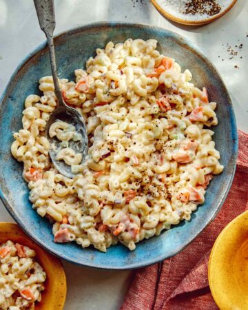 Hawaiian style macaroni salad in a bowl with serving bowls nearby.