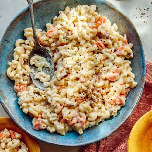 Hawaiian style macaroni salad in a bowl with serving bowls nearby.