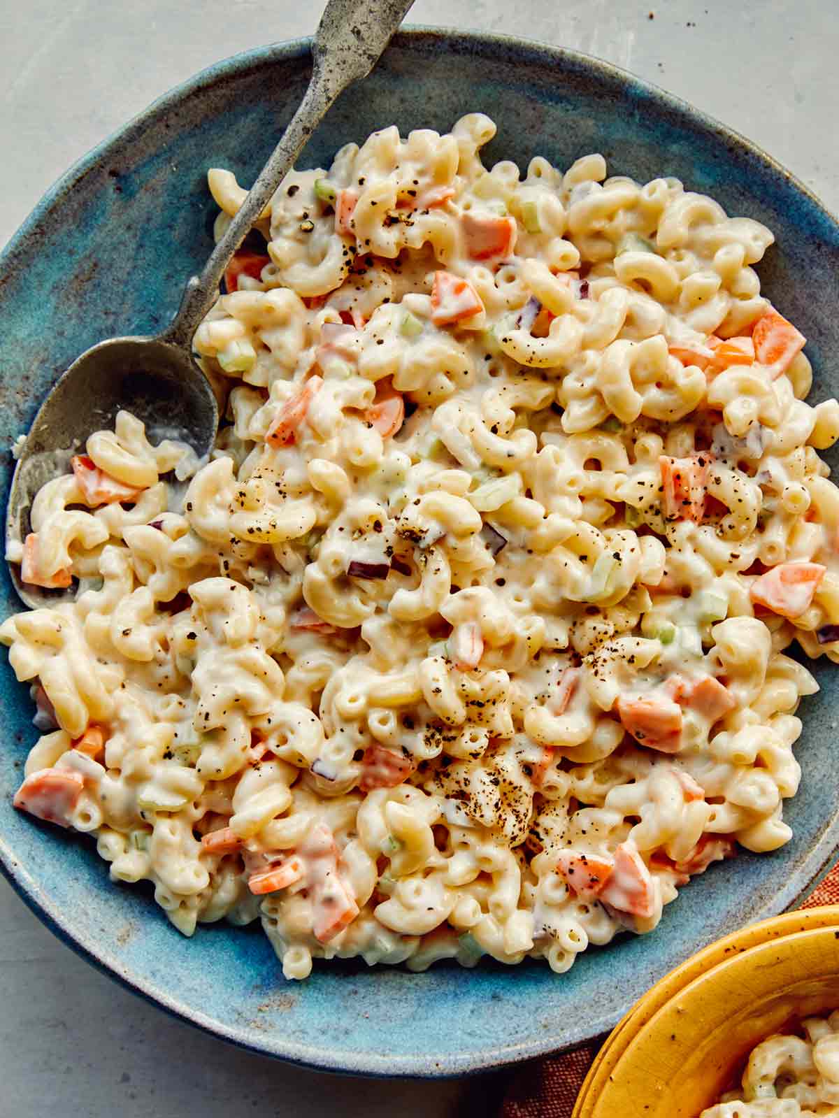 Macaroni salad made in the Hawaiian style in a bowl with a spoon in it.