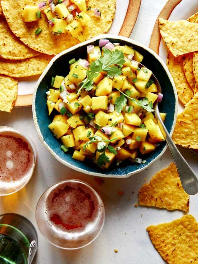 Mango salsa in a bowl with beer and chips. 