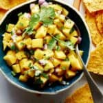 Mango salsa recipe in a bowl with chips.