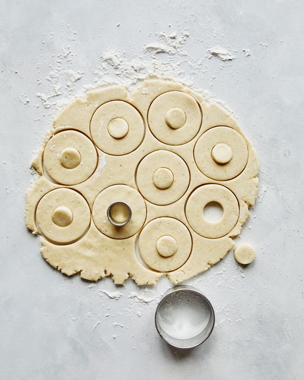 Donuts being cut out with a cutter. 