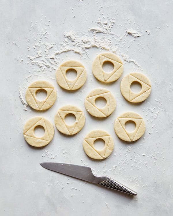 Old fashioned donuts being scored with a knife.