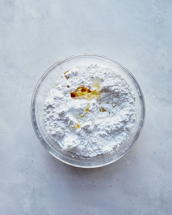 Ingredients for a vanilla glaze in a glass bowl.