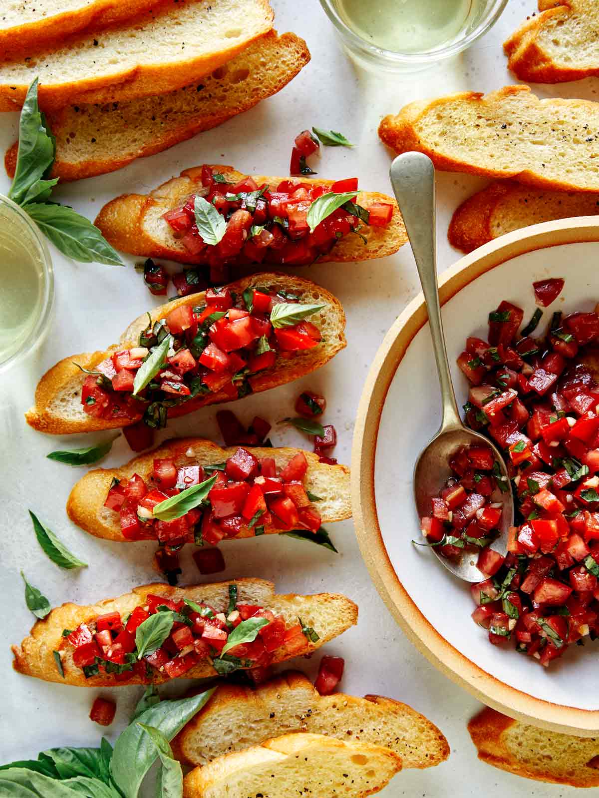 Brushetta ingredients on baguettes with basil on the side.