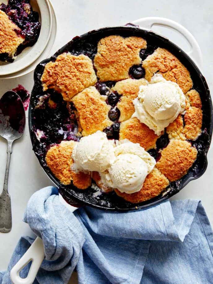 Blueberry cobbler recipe in a skillet with ice cream.