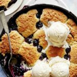 Blueberry cobbler recipe in a skillet with ice cream.