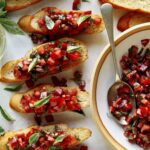 Brushetta ingredients on baguettes with basil on the side.