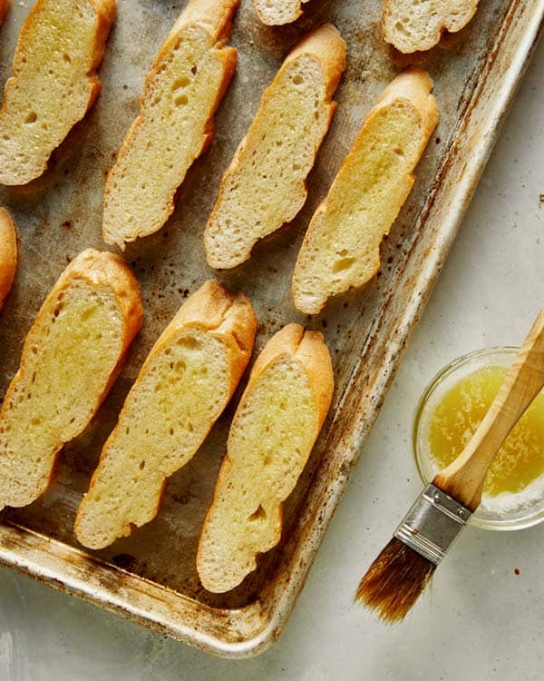 Brushing sliced baguettes with olive oil for bruschetta. 