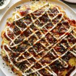 Okonomiyaki on a plate with fork next to it.