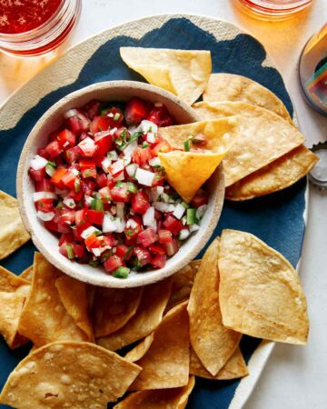 Pico de gallo in a bowl with chips on the side.