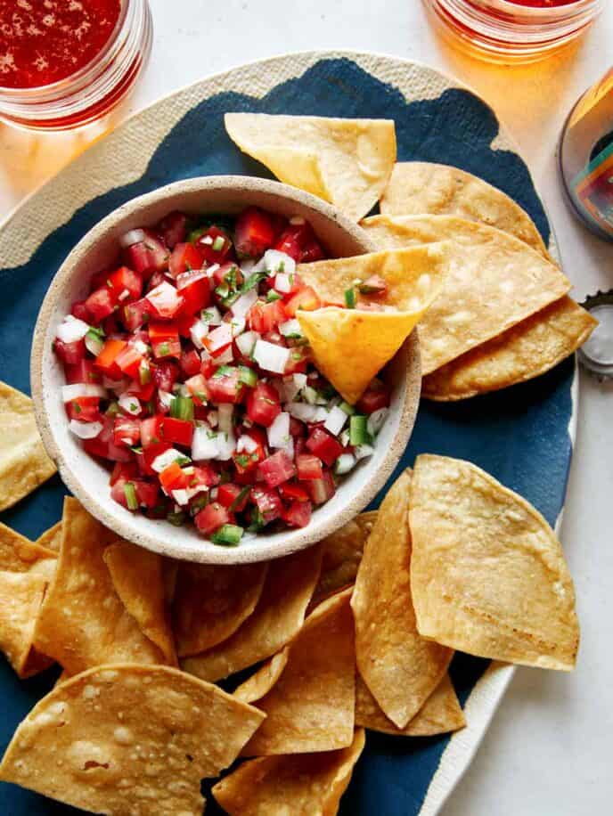 Pico de gallo in a bowl with chips on the side. 