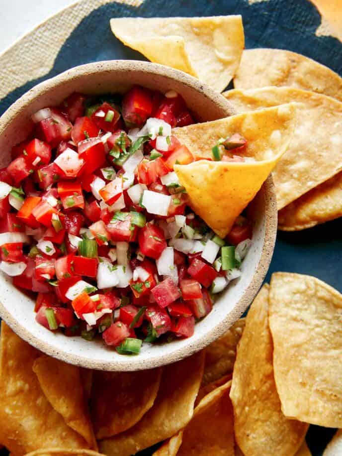 Pico de gallo recipe in a bowl with a chip in it.