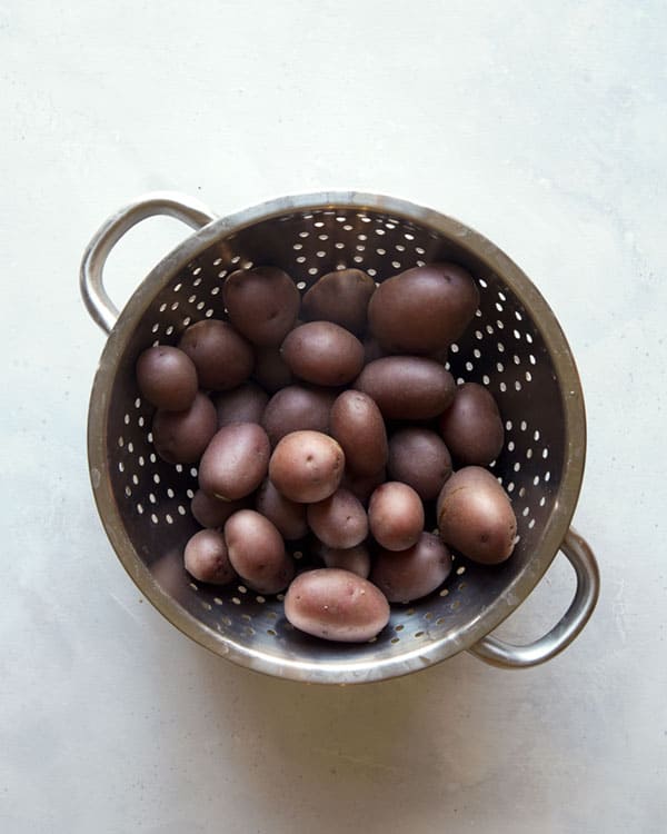 Red potatoes in a colander being drained for creamy potato salad. 