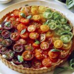 Tomato tart on a platter with white wine in the background.