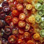 Tomato tart recipe on a platter with fresh tomatoes on the side.