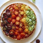 Tomato tart recipe on a platter with fresh tomatoes on the side.