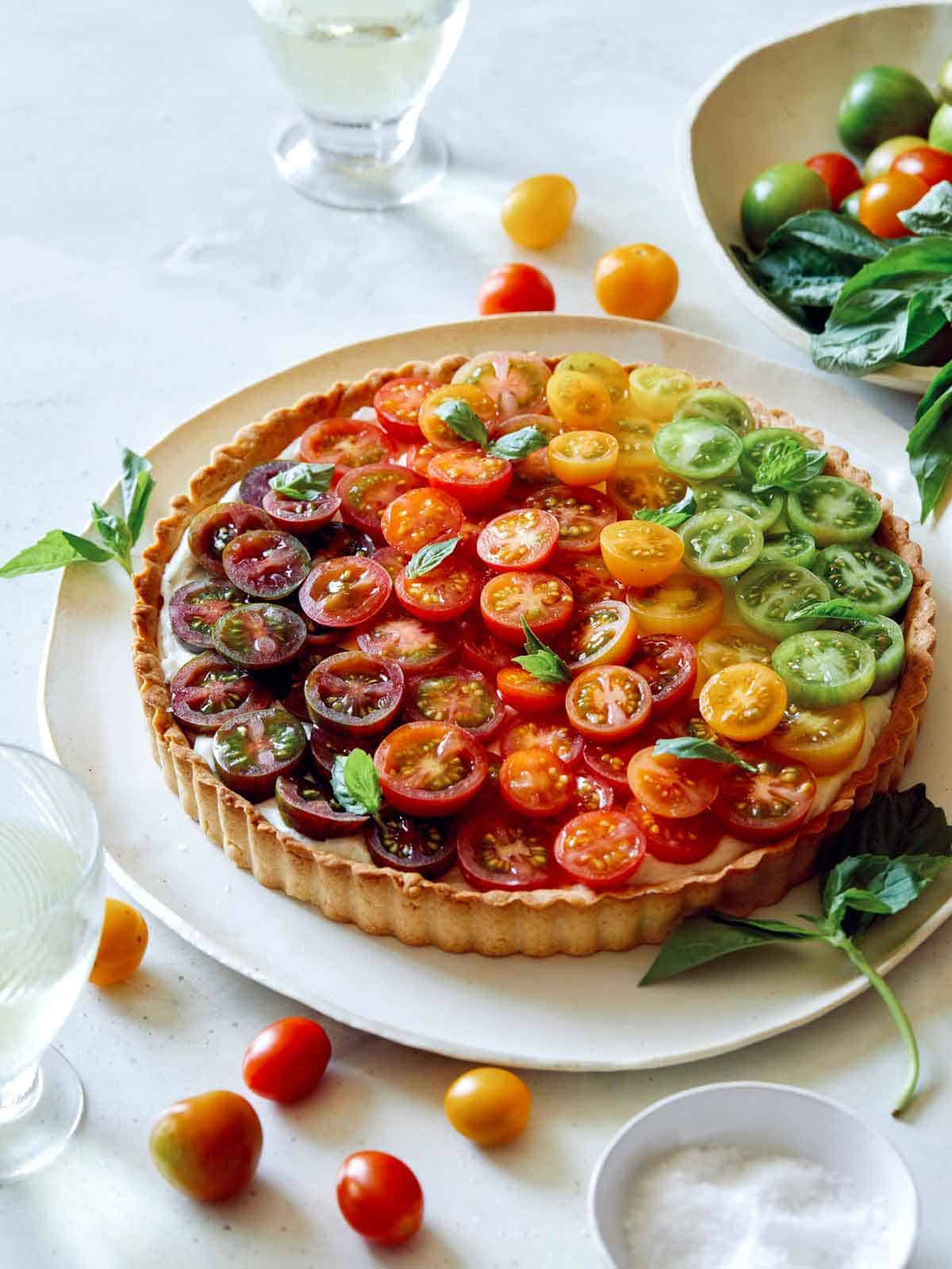 Tomato tart on a platter with white wine in the background.