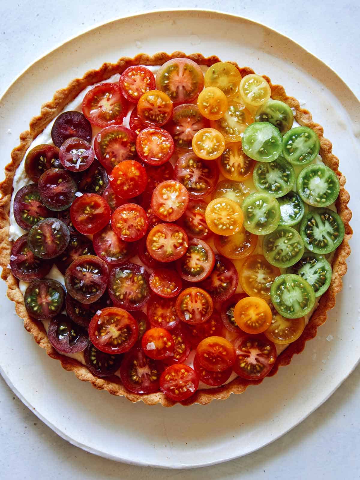 Close up on an ombre tomato tart with different colors of tomatoes. 