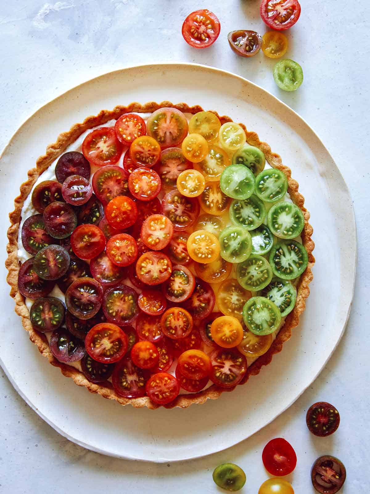 Tomato tart recipe on a platter with fresh tomatoes on the side.